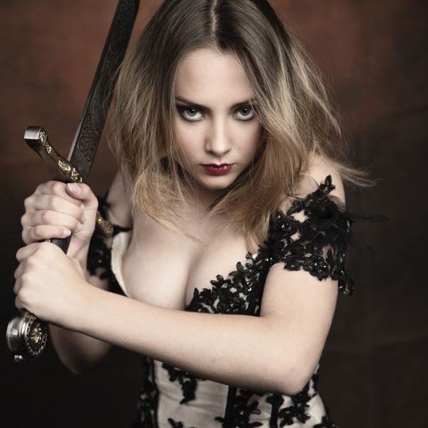 Cosplay guerrière en robe de dentelle noire, épée brandie près du visage — Fabrice Fiorucci Photographe